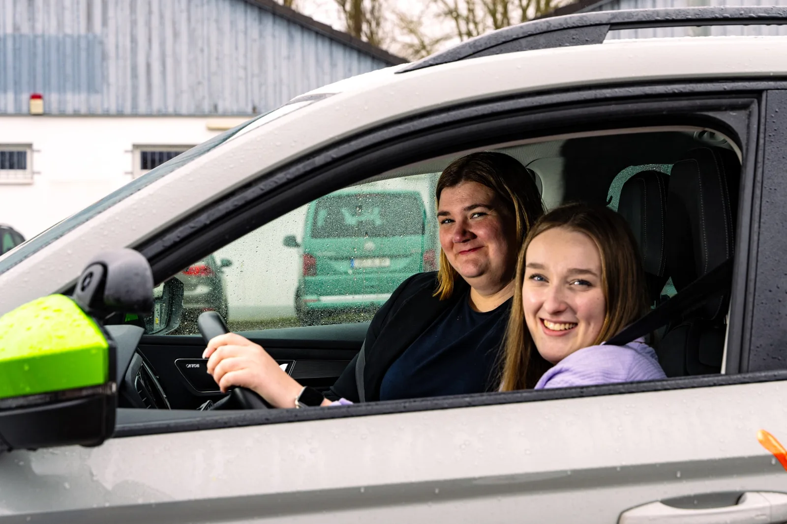Fahrlehrerin und Fahrschülerin lachen gemeinsam im Fahrschulauto